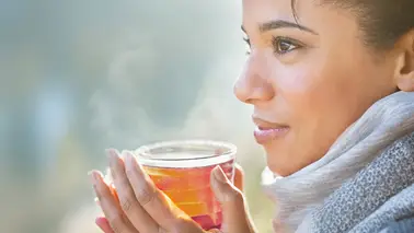 Femme qui regarde au loin avec une tasse de thé