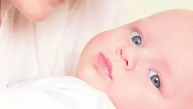 Gros plan tendre d'un nouveau-né aux yeux grand ouverts, blotti contre le visage de sa mère souriante